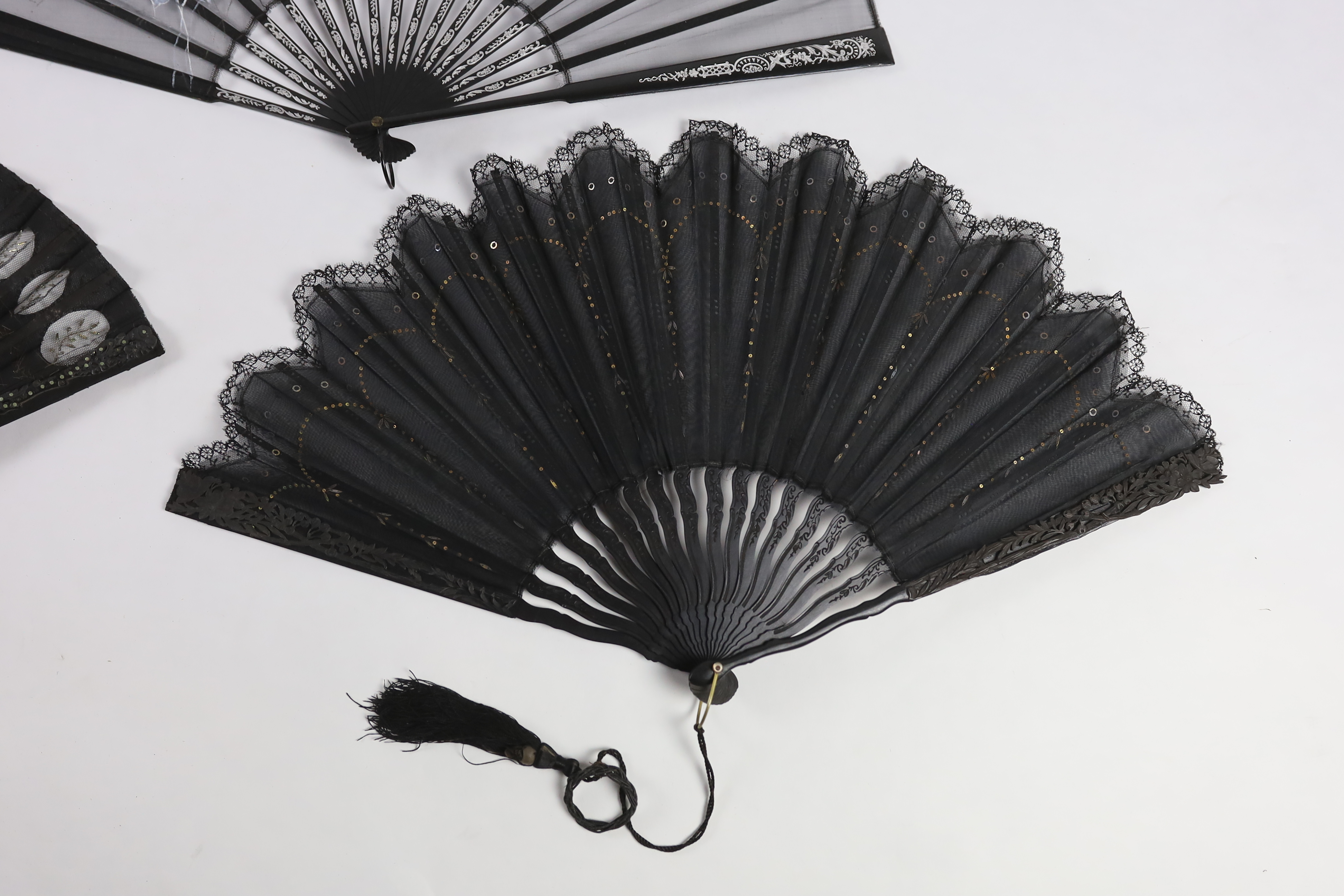 An Edwardian black silk and ornate sequin fan, a similar fan with carved ebony guards and a fine gauze fan with painted sprig and butterfly decoration (3)